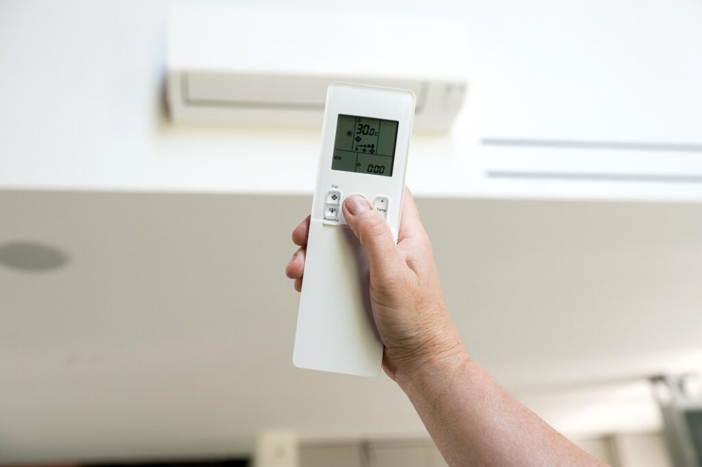 Close-up of the hand holding the remote control of the air conditioner.